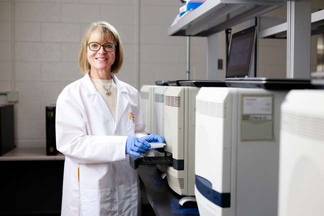 Woman in white coat in front of machines