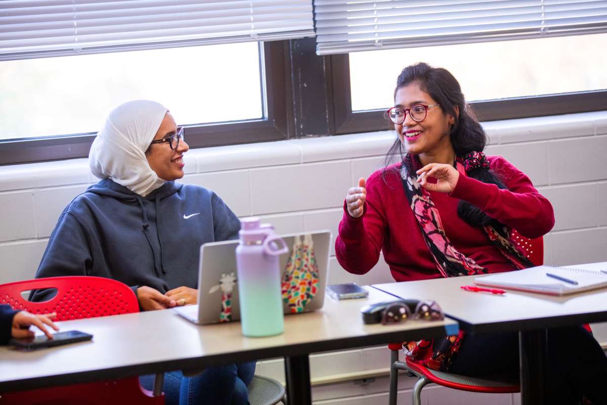 three women talking in a classroom