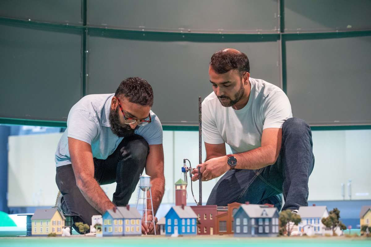 two men crouching over a model city for tornado simulator 